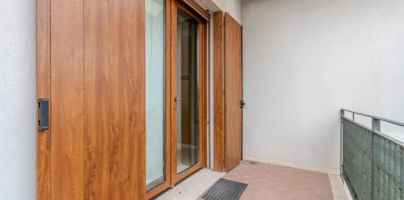 A balcony with wooden doors opening onto a tiled outdoor area.