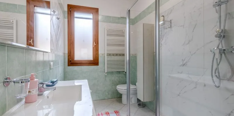 A tiled bathroom with a sink, toilet, and glass shower.
