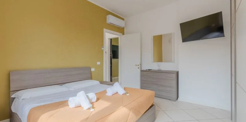 Un dormitorio con una cama, un televisor en la pared y una cómoda.