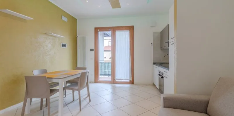 A dining area with a table beside a glass door opening to a balcony.