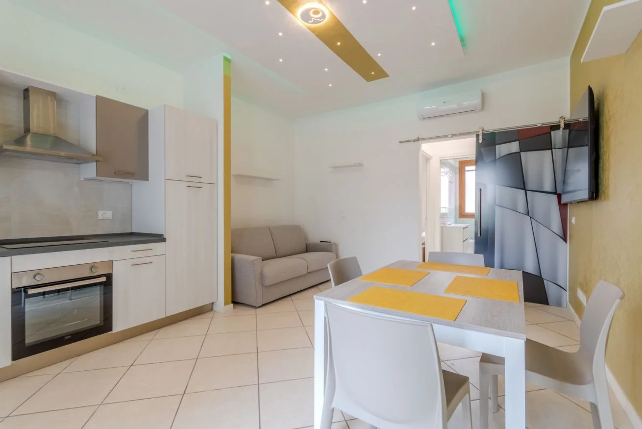 A combined kitchen and dining area with a small sofa and a tiled floor.