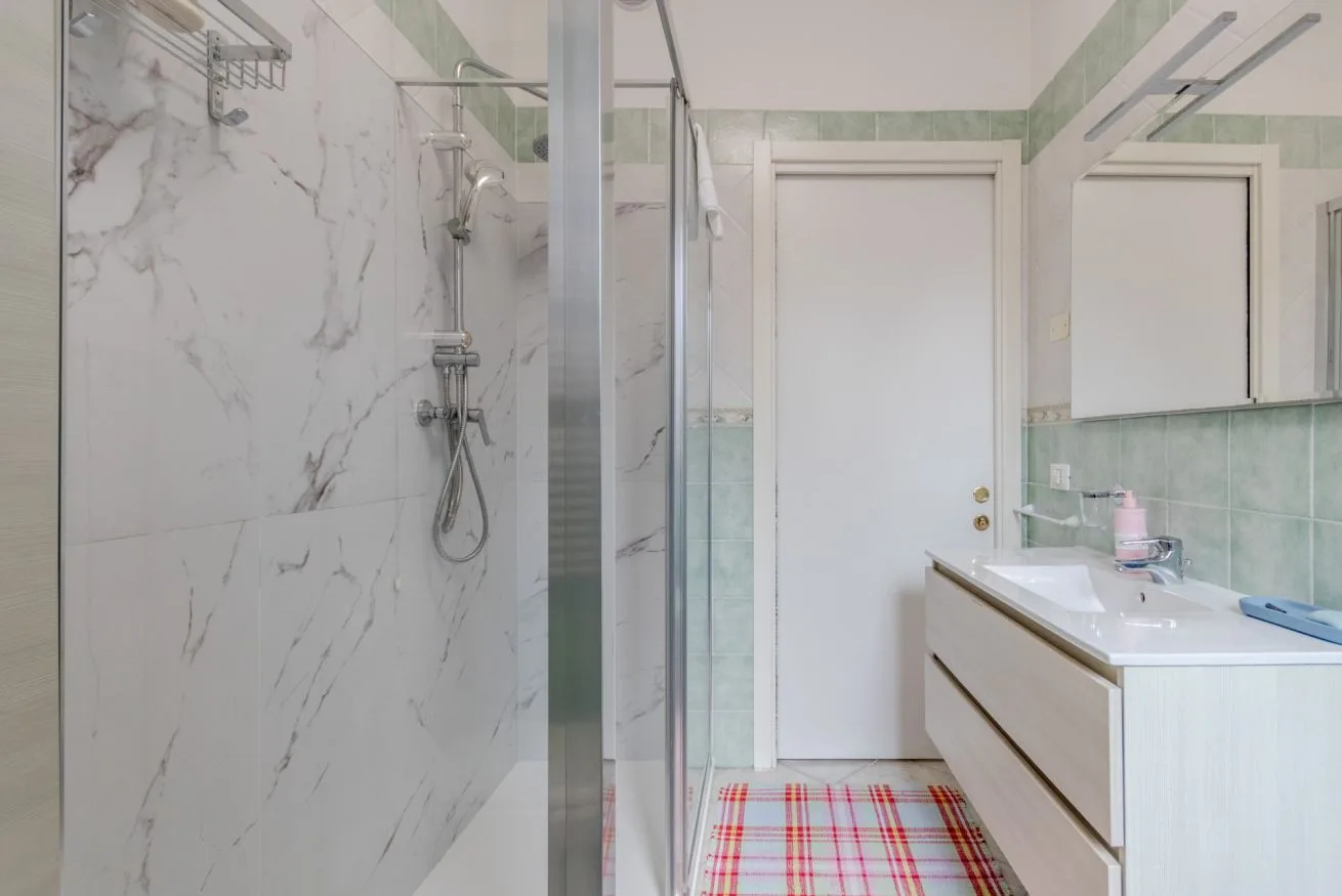 A bright bathroom with a glass shower and a long vanity.