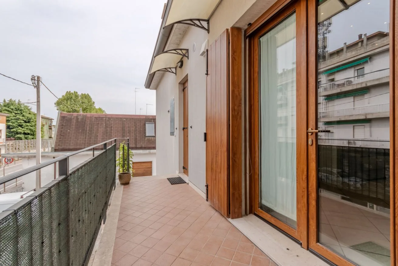 A tiled balcony walkway runs beside wooden-framed glass doors.