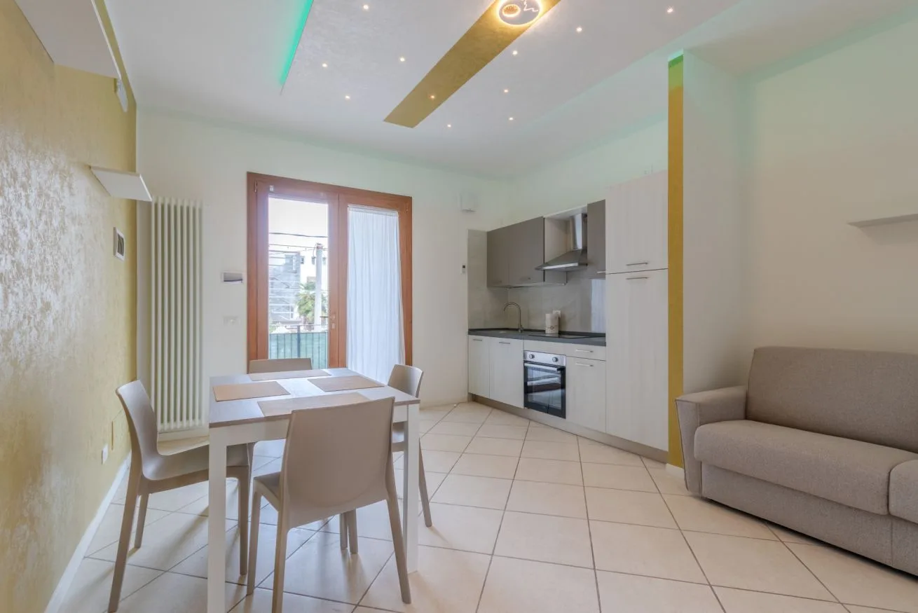 A bright dining and kitchen area with a table and seating beside a window.