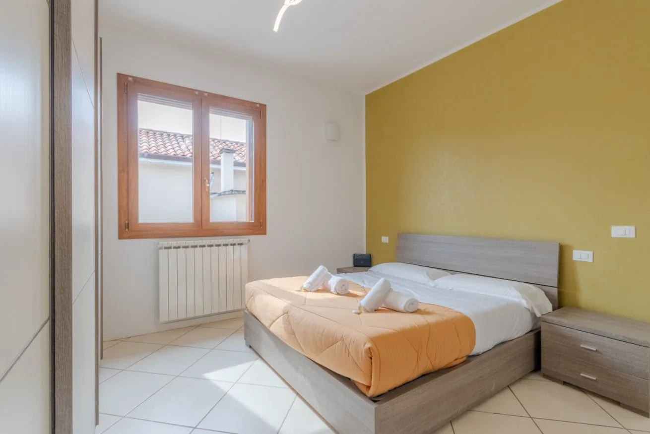 A bedroom with a bed, bedside table, and window.