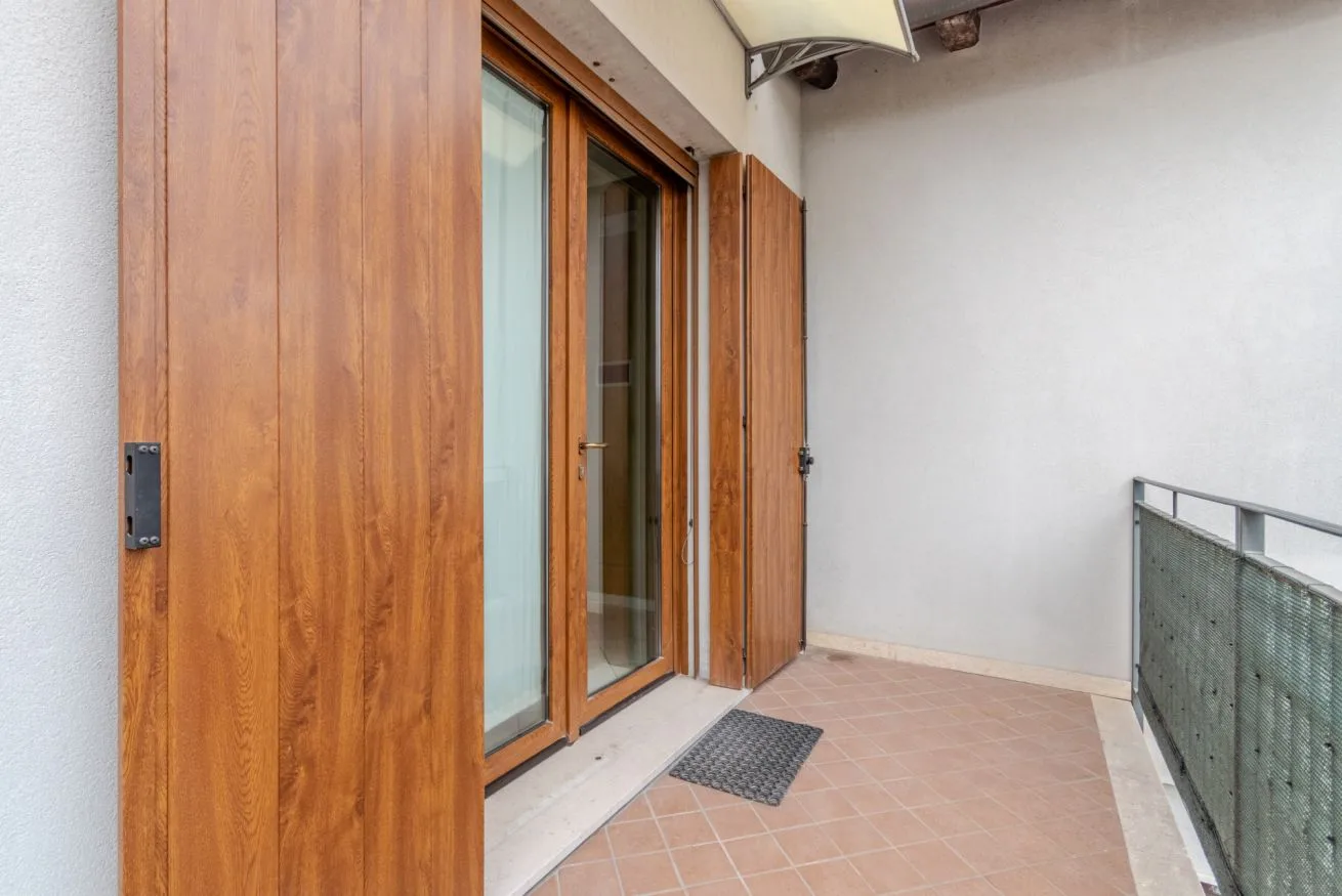 A tiled balcony beside a wood-framed glass door.