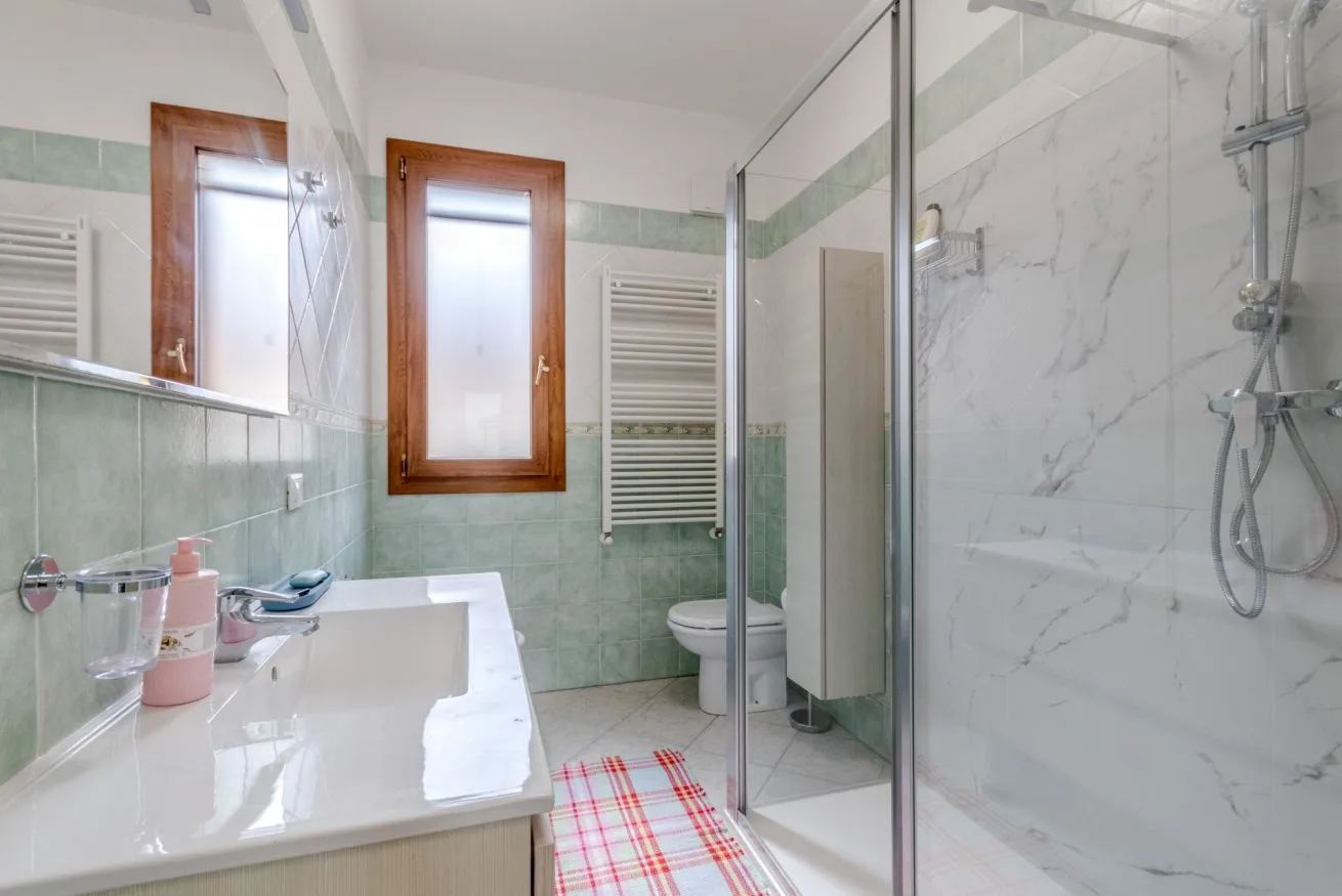 A bathroom with a glass shower, sink, and toilet.