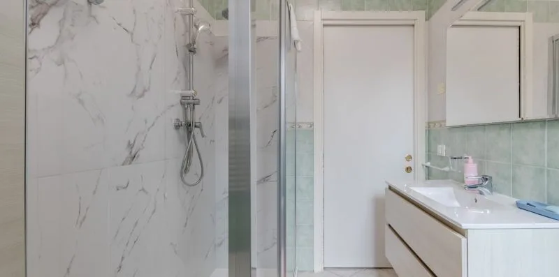 A bathroom with a glass shower and a sink vanity.