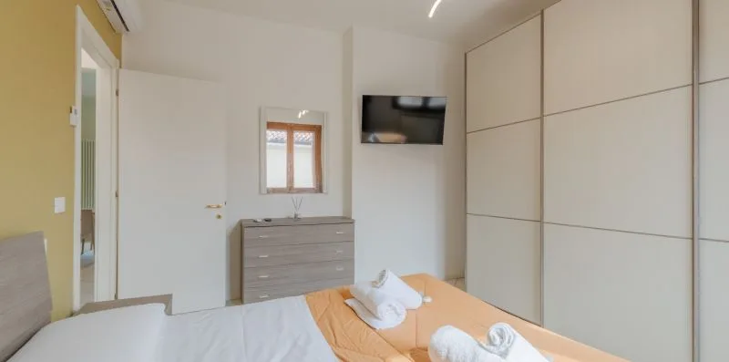 A bedroom with a bed, dresser, and large built-in wardrobes.