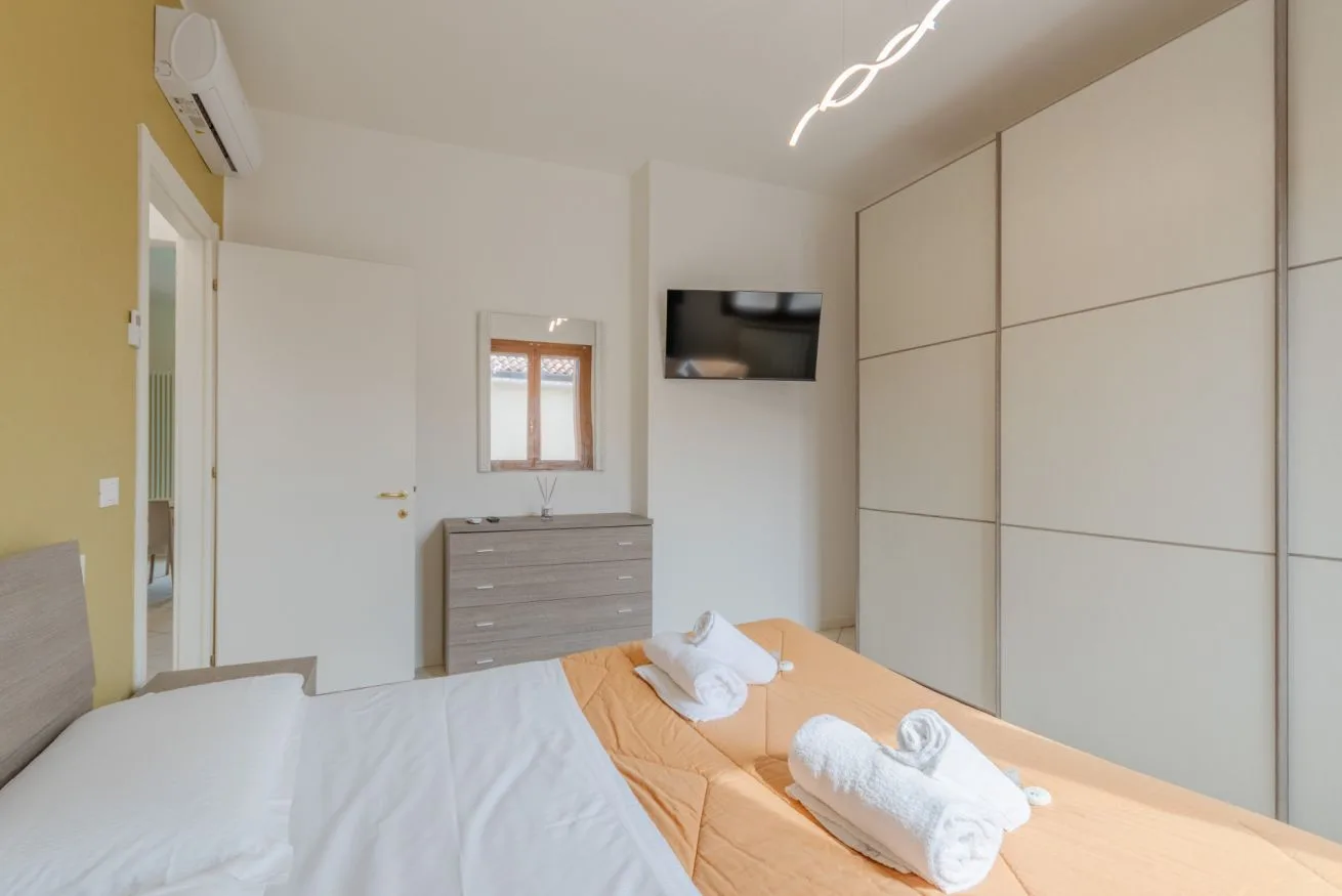 A bedroom with beds, a dresser, and a wall-mounted television.