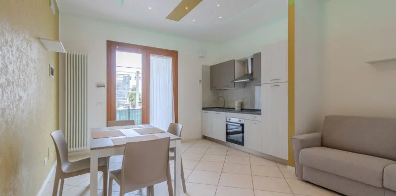 Una luminosa estancia diáfana con mesa de comedor, cocina y zona de estar.
