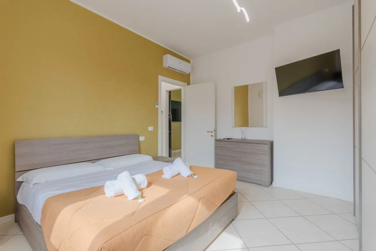 A bedroom with a bed, a dresser, and a wall-mounted television.