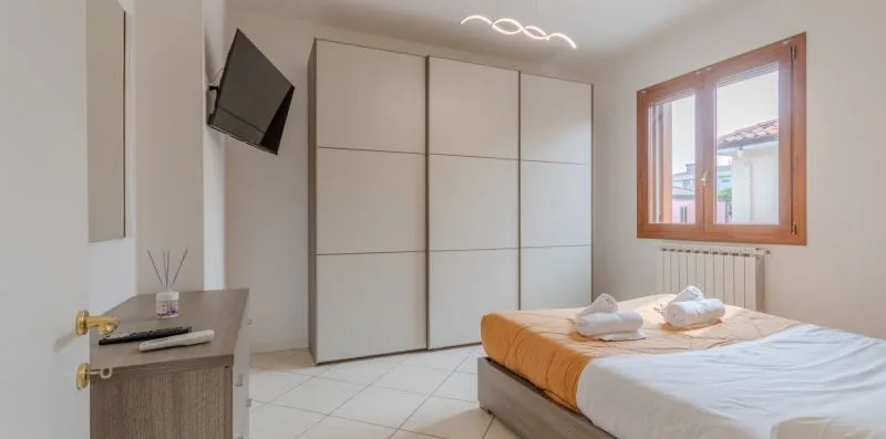 A bedroom with a bed, built-in wardrobe, and a window.