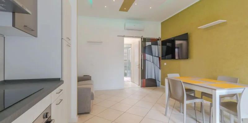 Un comedor luminoso con una mesa y sillas junto a un televisor montado en la pared.