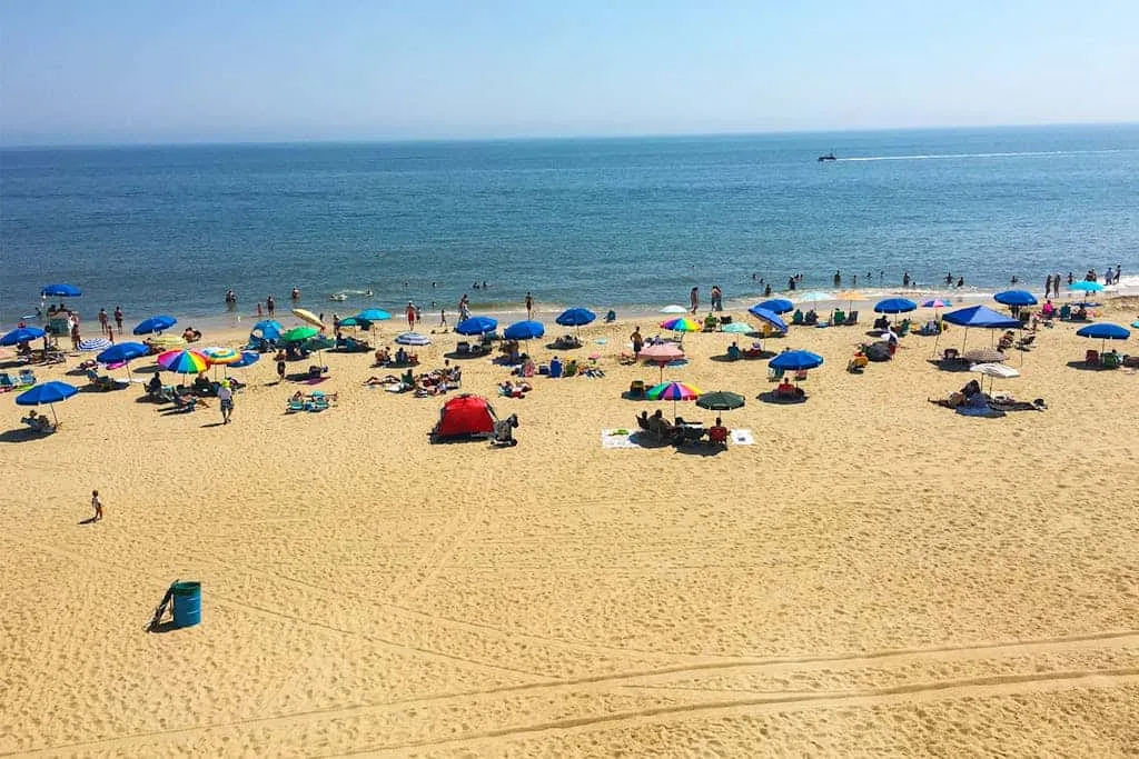 A sandy beach with colorful umbrellas and the sea beyond.
