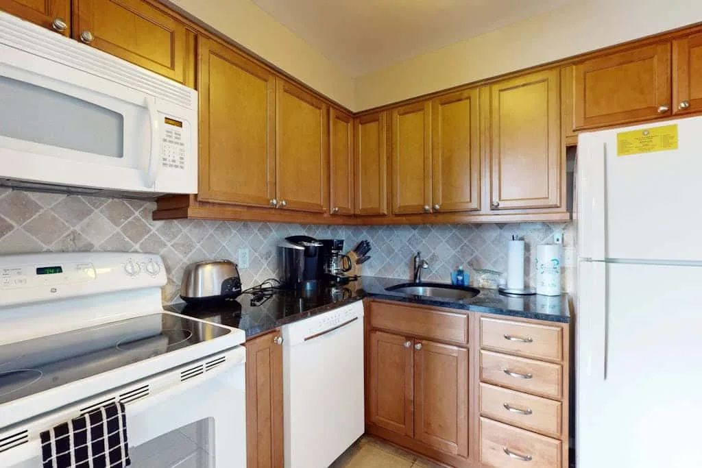 A kitchen with wooden cabinets, a stove, and a refrigerator.