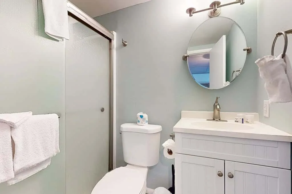 A bathroom with a vanity, sink, toilet, and glass shower.