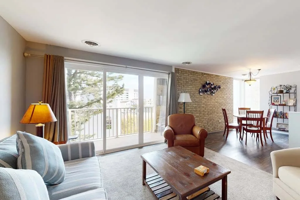 A living room with seating, a coffee table, and sliding glass doors opening to a balcony.