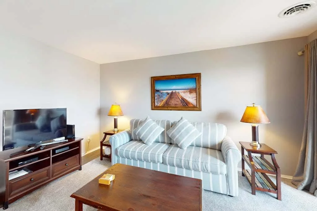 A living room with striped seating, a television, and a wooden coffee table.