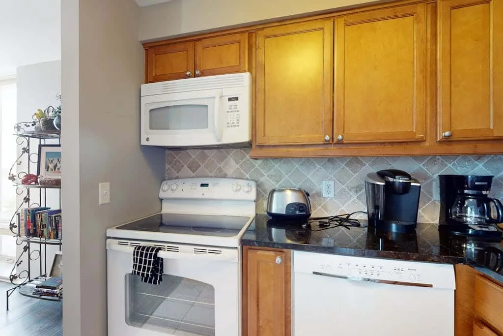 A kitchen counter with wooden cabinets, a microwave, and small appliances.