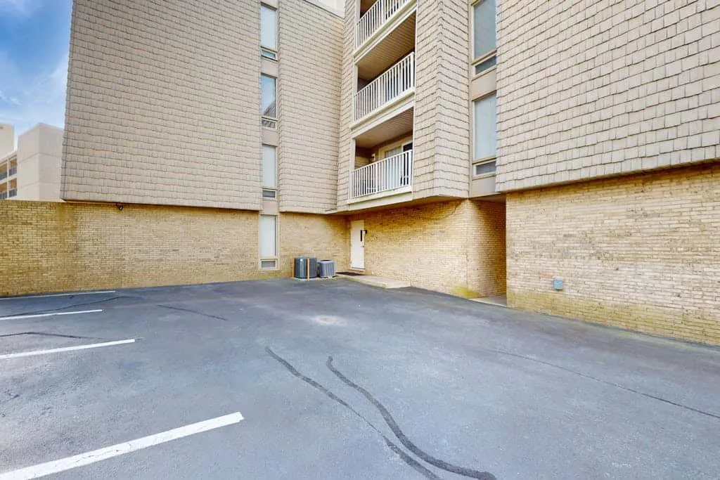 An asphalt parking area beside a multi-story brick building.