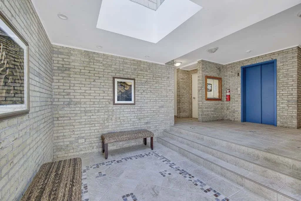 A tiled lobby with a blue elevator and raised landing.