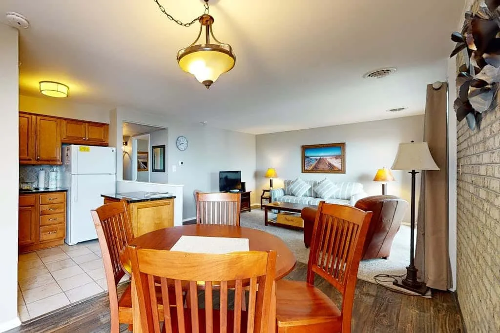 A dining area opens onto a living room with a sofa and television.