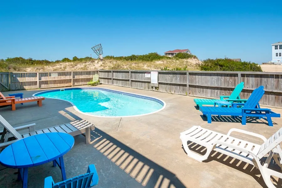 An outdoor pool area with blue seating beside the water.