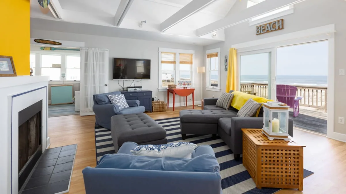 A bright living room with seating arranged around a television and fireplace.