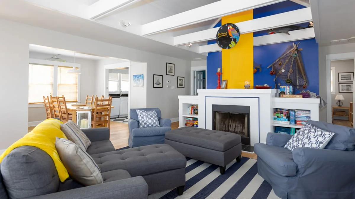 A bright living room with blue seating, a fireplace, and a colorful wall mural.