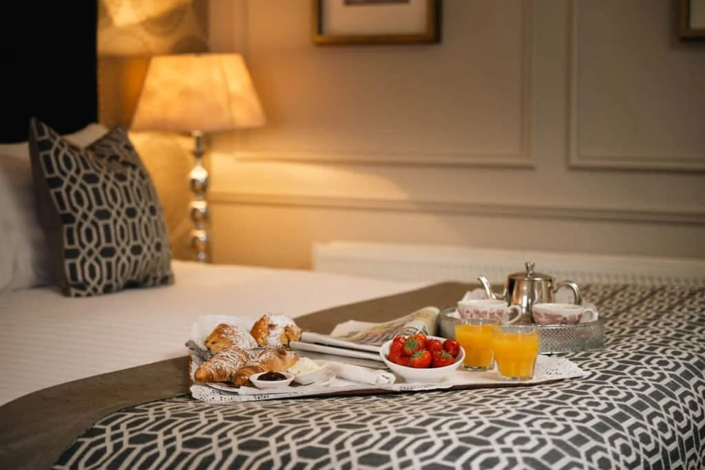Cama con bandeja de desayuno y textiles decorativos.