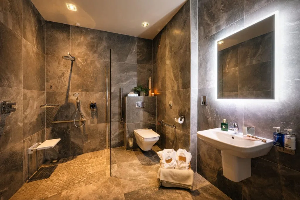 Baño accesible con ducha a ras de suelo y barras de apoyo.