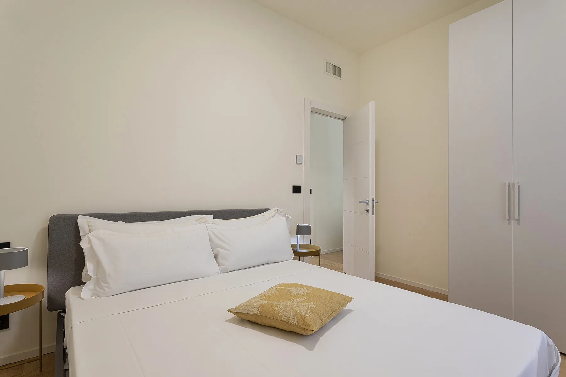 A bedroom with a neatly made bed and a wardrobe.