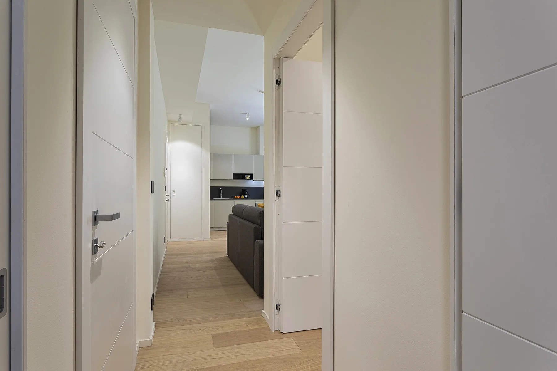 A hallway opens onto a living area and kitchen.