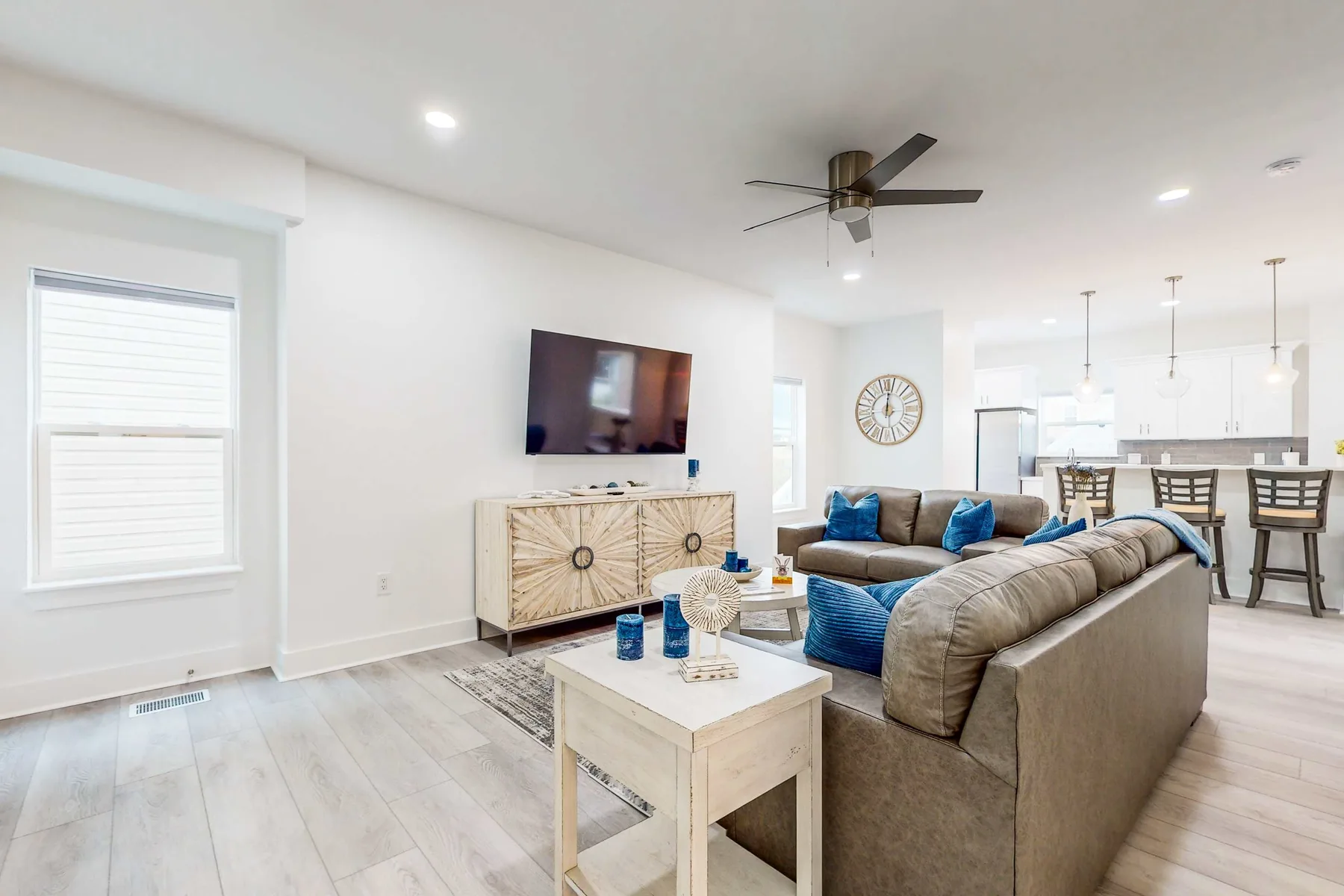 A bright living room with a television and seating beside an open dining area.