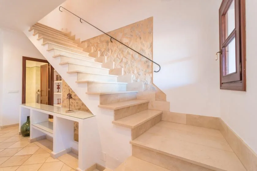 A tiled interior stairway with pale steps and a slim metal handrail.