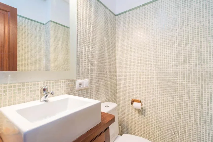 A tiled bathroom with a sink, mirror, and toilet.