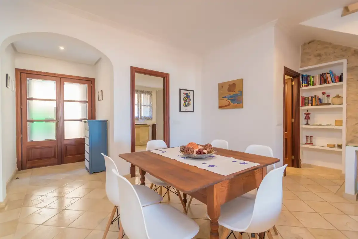 A dining room with a wooden table and white chairs.