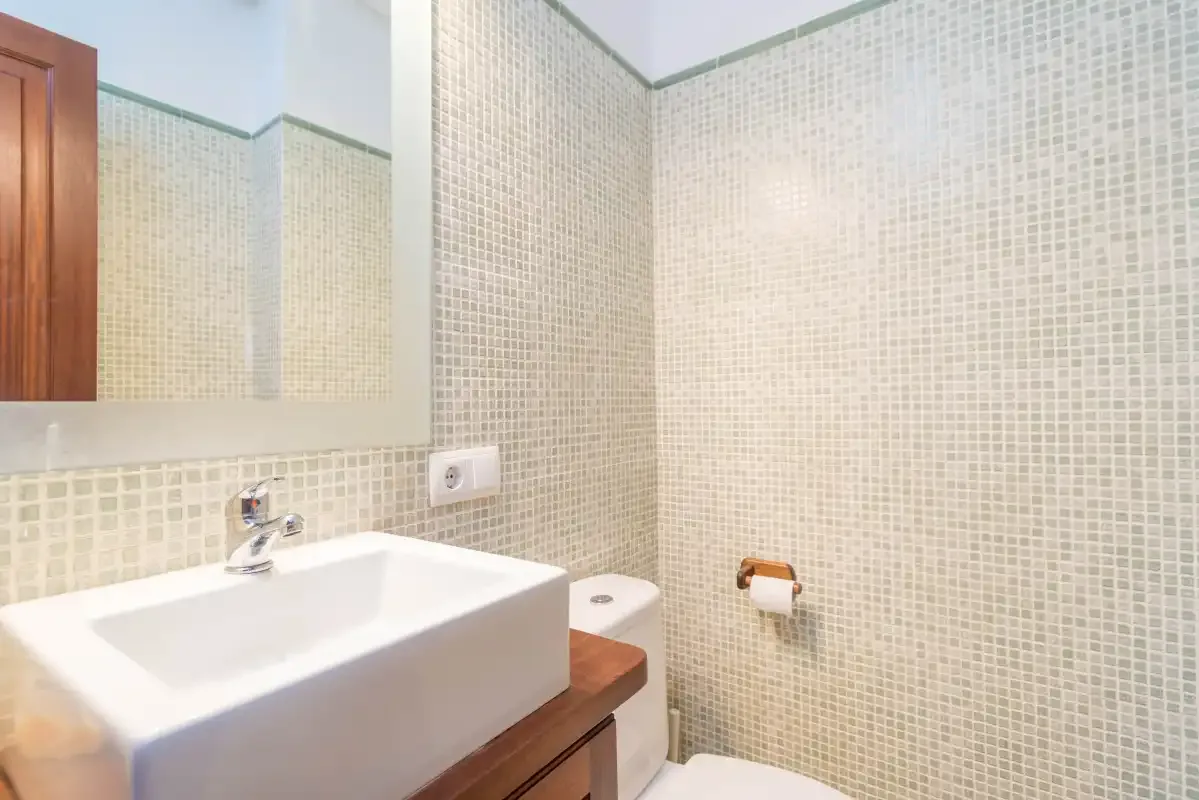 A bathroom with a white sink, tiled walls, and a mirror.