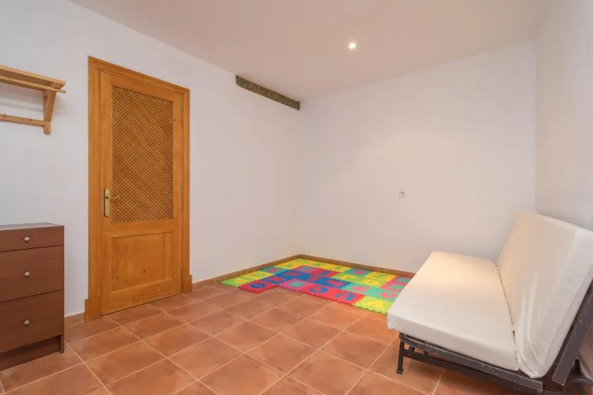 A tiled room with a wooden door and a white seating area.