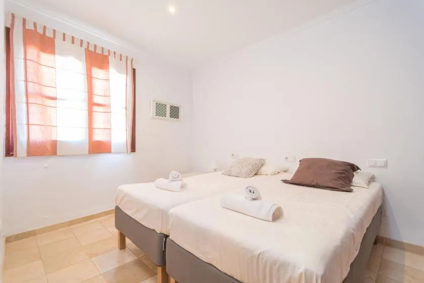A bright bedroom with two beds dressed in white linens.