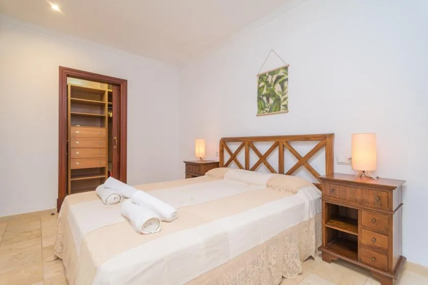 A bedroom with a double bed, wooden headboard, and matching bedside furniture.