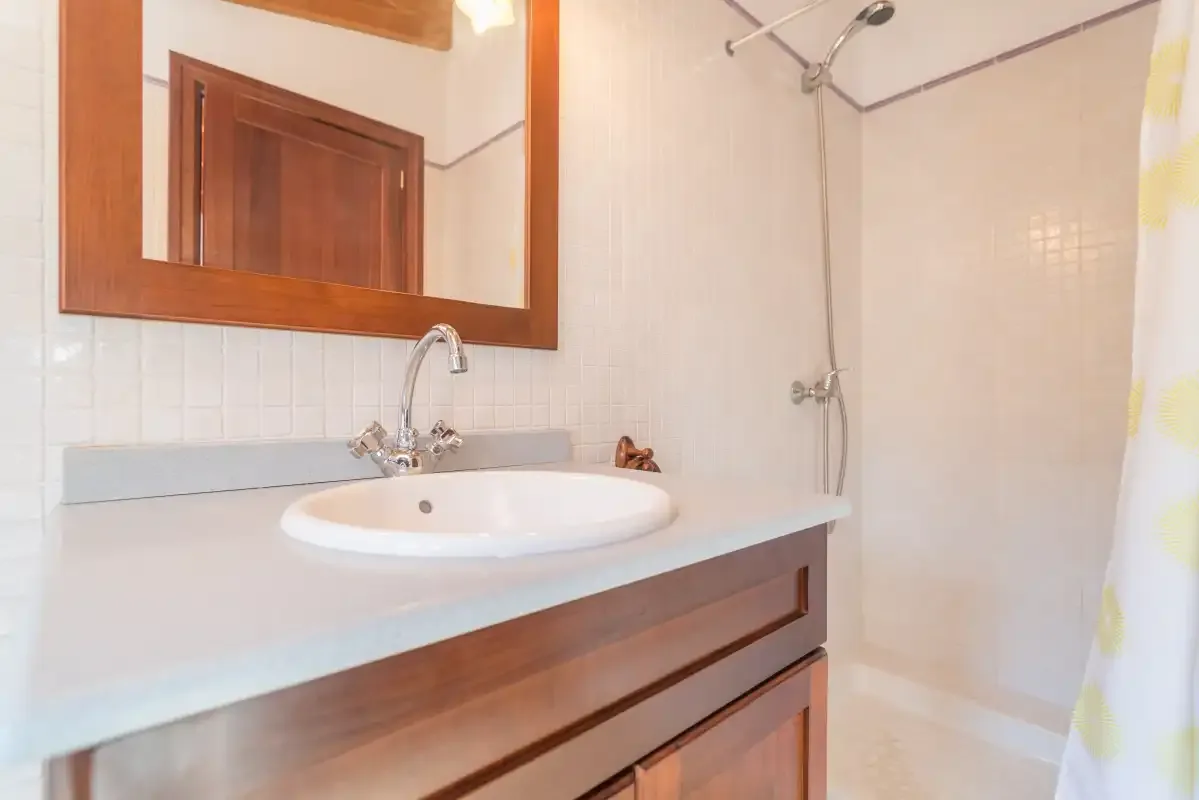 A bathroom with a sink, mirror, and shower.