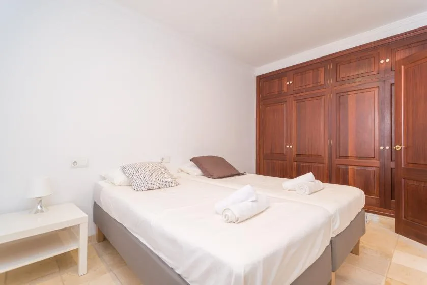 A bedroom with a neatly made bed and built-in wooden wardrobes.