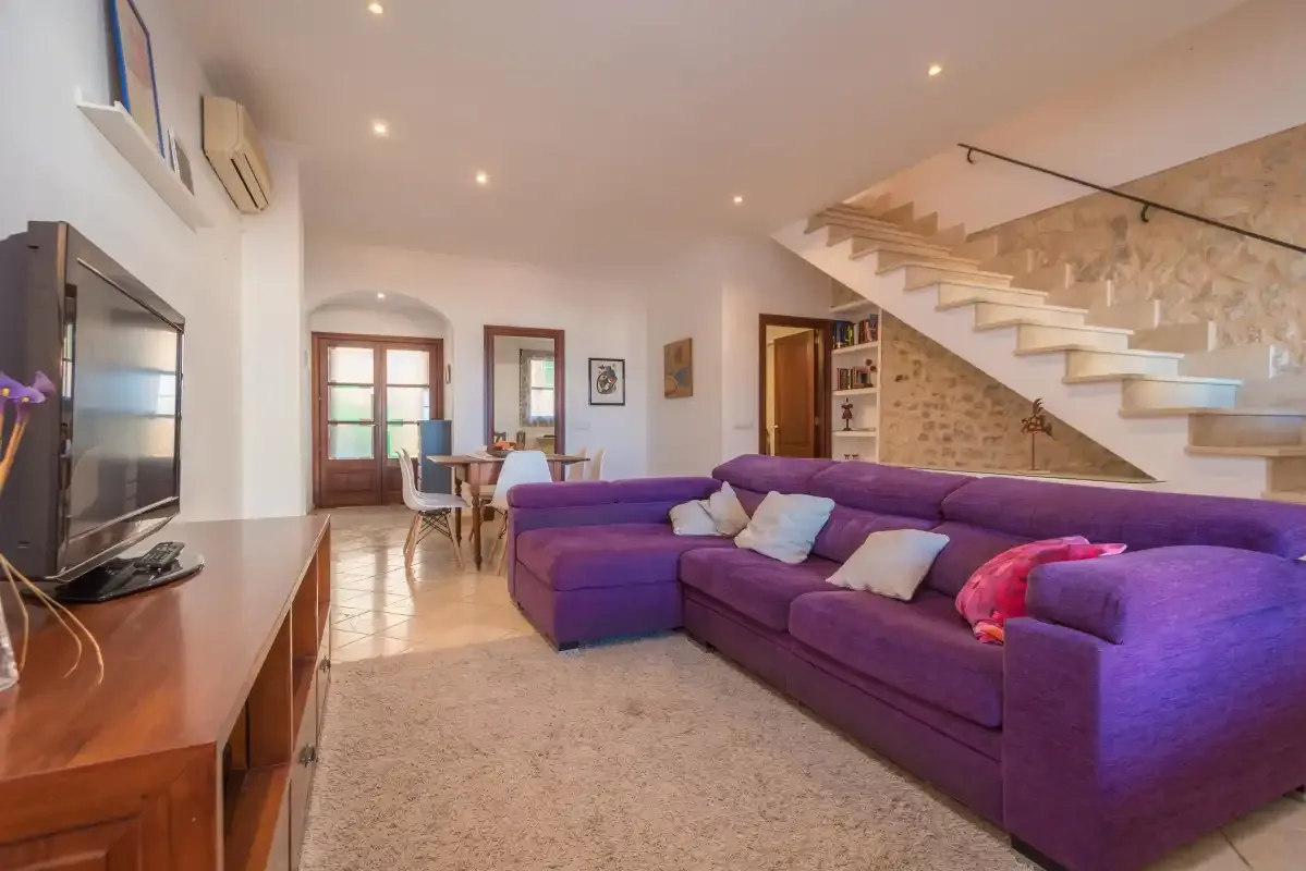 Living room with purple seating and a staircase along the wall.