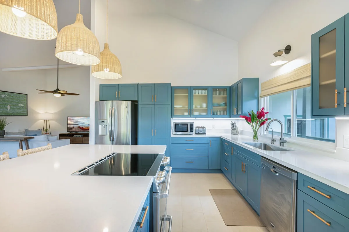Una cocina luminosa con gabinetes azules, una isla grande y lámparas colgantes.