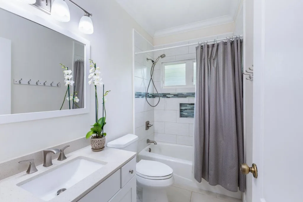 Un baño luminoso con lavabo, inodoro y bañera detrás de una cortina.