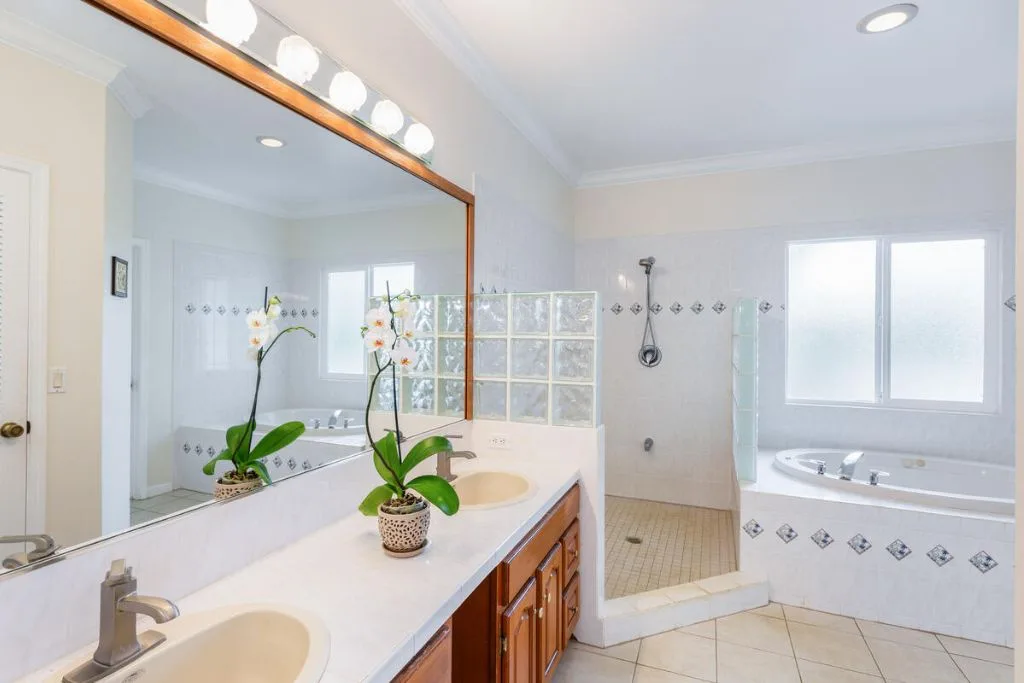 Un baño luminoso con un tocador largo, espejos y una bañera.
