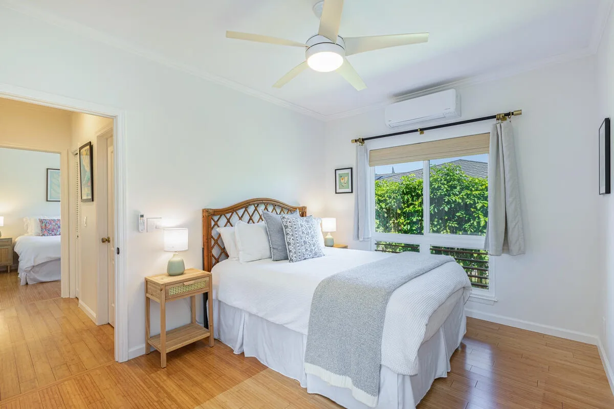 Un dormitorio luminoso con una cama junto a una ventana con vistas a la vegetación.