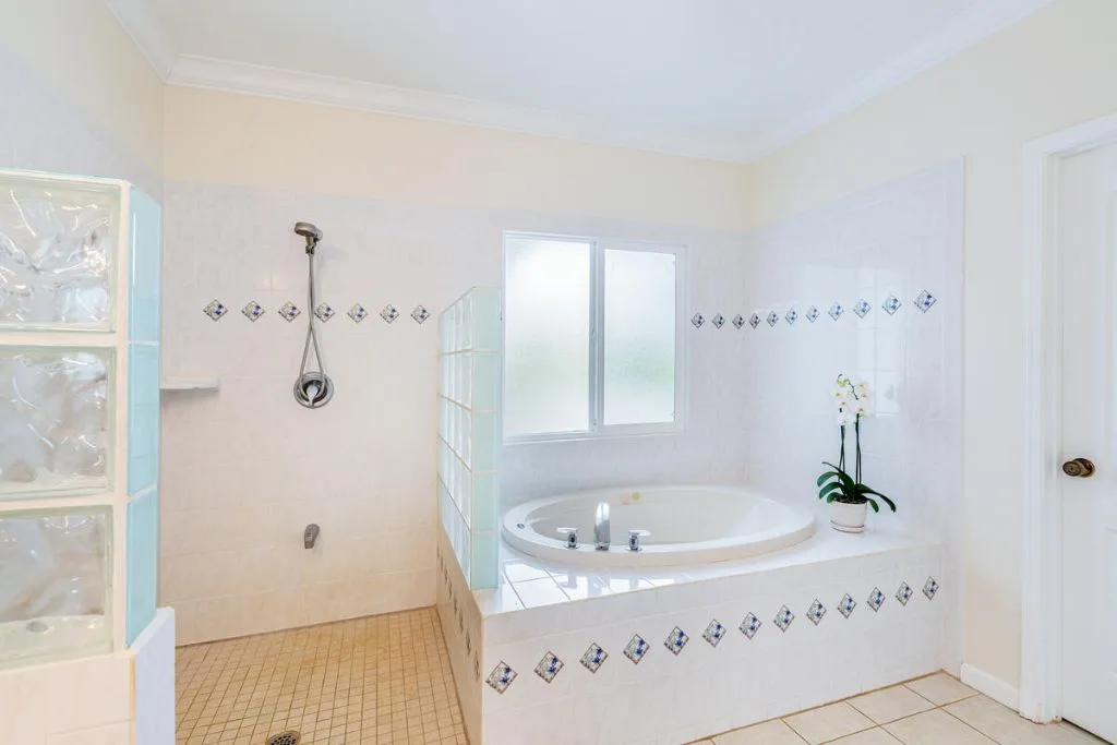 Un baño alicatado con una bañera empotrada bajo una ventana esmerilada.